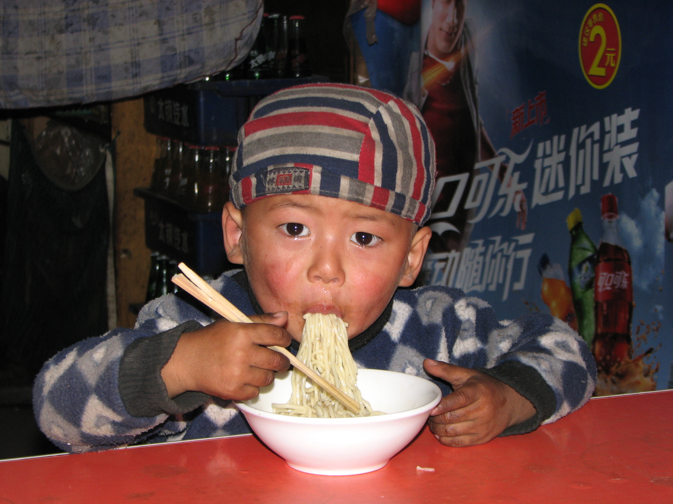A boy eating noodles in a Muslim noodle shop